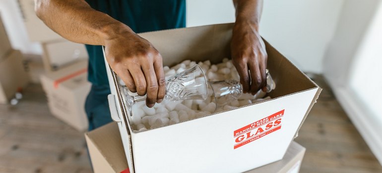 man packing glasses into a box