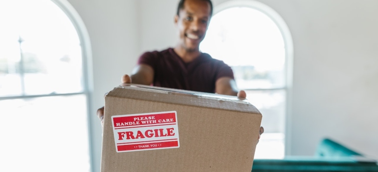 a picture of our white glove mover in orange county holding a box labeled fragile