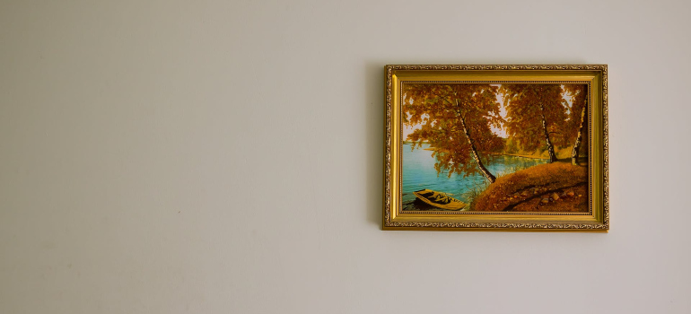 a painting of a boat in a river, hanging on the wall