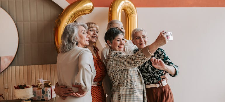 5 elderly women celebrating the sixtieth birthday of one of them, illustrating socializing as one of the top reasons why seniors are moving to Orange County