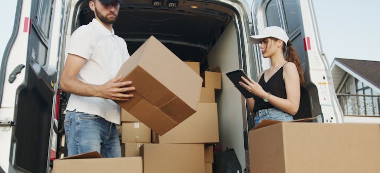 two professional office movers standing next to a van 