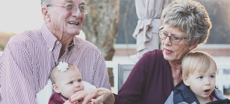 two elderly people holding two babies