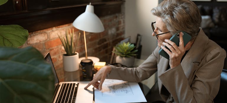 a woman talking on the phone and pointing at her laptop