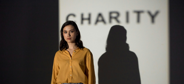 a woman standing in front of the shadow of the word "charity"