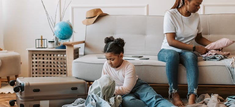 a mother and her daughter are packing clothes into suitcases