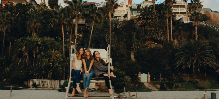 three friends sitting on a lifeguard's chair at the beach