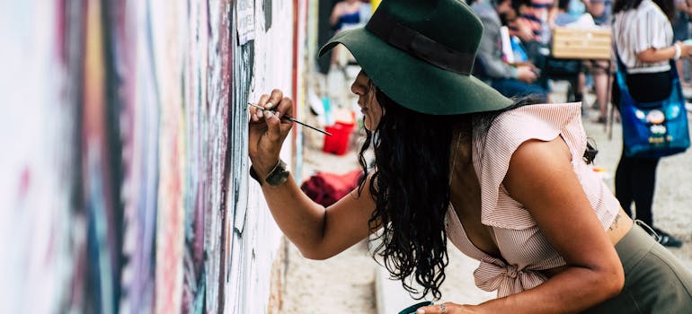 a woman painting a wall with a small paintbrush, which is part of one of the best free attractions in Santa Ana