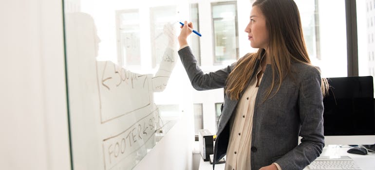 a woman in a suit writing on a whiteboard