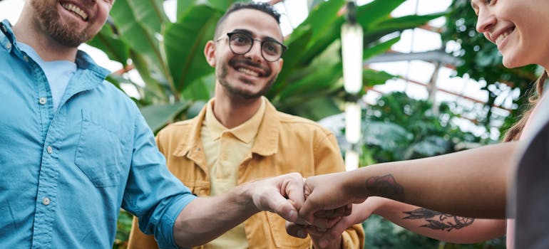 three people join hands in support of one another after deciding to fight addiction by moving to a coastal city