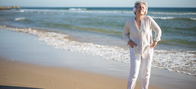 an elderly woman in white enjoying the beach