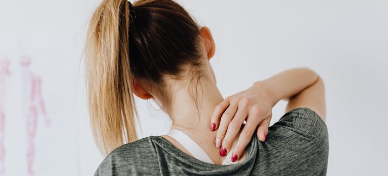 a woman touching her injured neck in understanding why you should hire piano movers