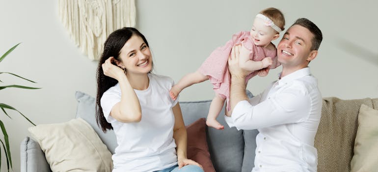 a family consisting of two parents and a baby, smiling for the camera