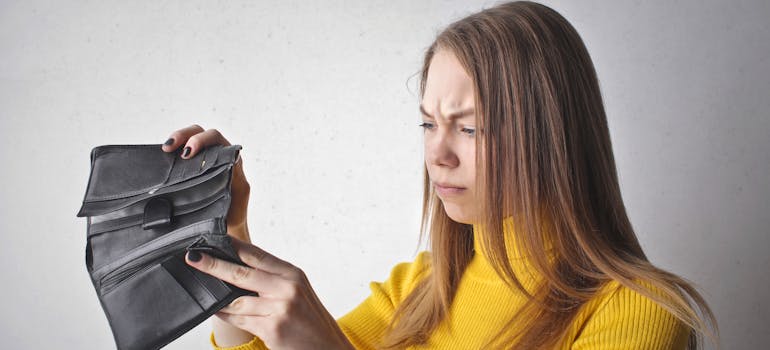 a woman looking at her empty wallet in disbelief