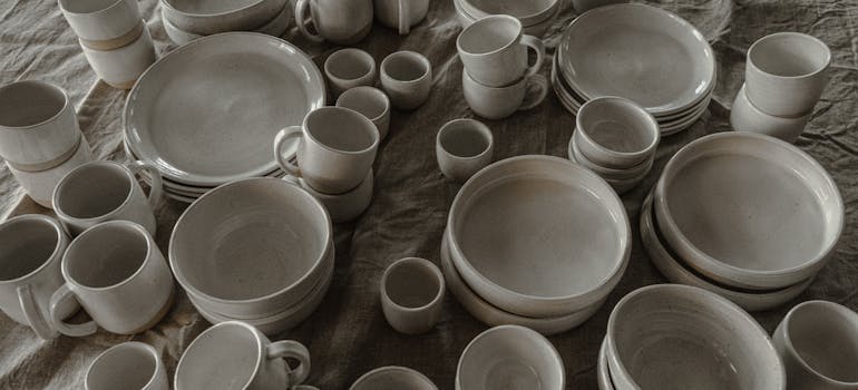 lots of porcelain cups and plates, arranged on a bed