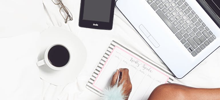 a person surrounded by a laptop, tablet, and a cup of coffee while making a plan on how to de-stress your move