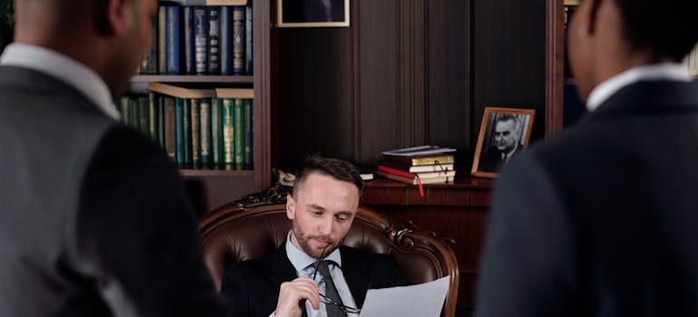 two people in a lawyer's office, waiting for him to read a document