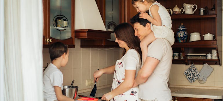 a family of four preparing lunch together in the kitchen