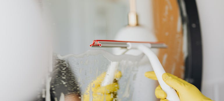 someone cleaning a mirror while wearing yellow gloves