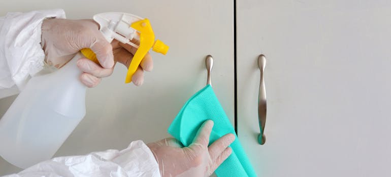 a person cleaning white kitchen cabinets