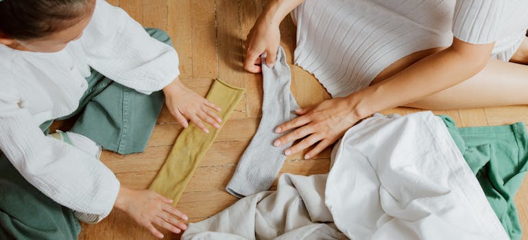 a woman and a child are folding socks while sitting on the floor