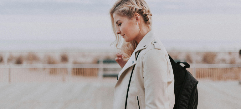 a woman walking around with a smile on her face and a black backpack on her shoulder