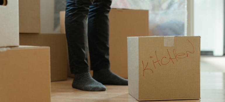 a man standing among the cardboard boxes and thinking about how to organize an eco-friendly move