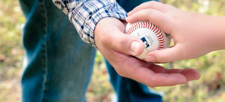 a child giving a baseball to a man