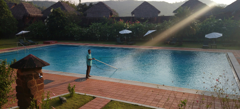 a man skimming a swimming pool with a smile on his face