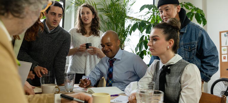 a group of employees gathered around a table, talking about something