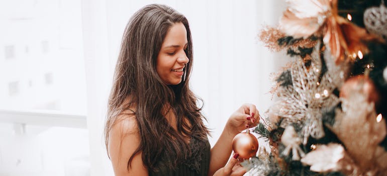 a woman putting ornaments onto a Christmas tree