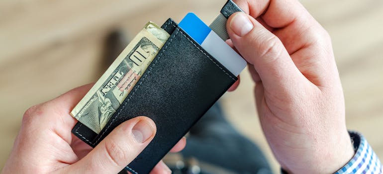 a man going through his wallet and wondering whether to buy or rent a house in Long Beach