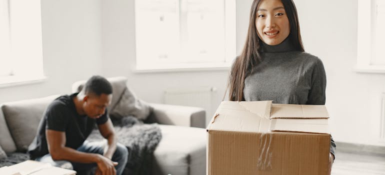 a woman proudly holding a cardboard box after artfully packing everything in it