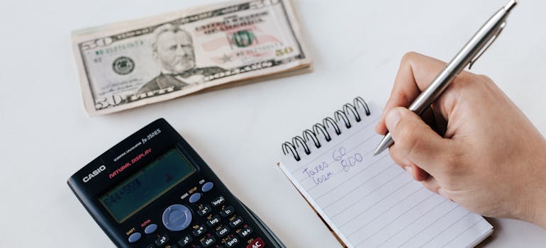 a person doing budget analysis with a calculator and a notepad