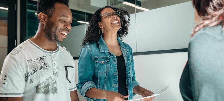 two people with smiles on their faces, taking a contract from another person