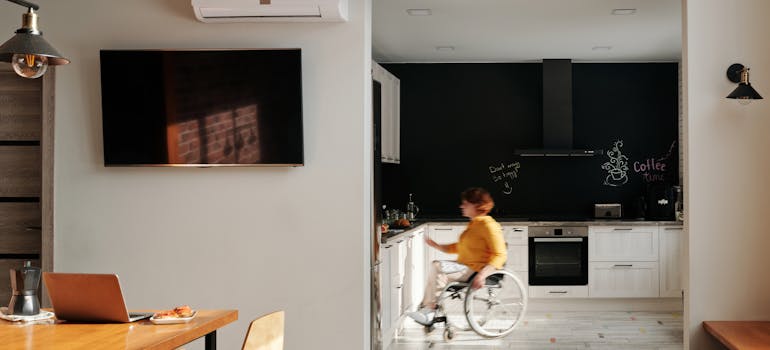 a woman in a wheelchair searching for something in the kitchen