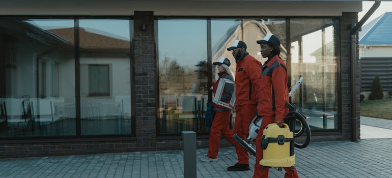 three people carrying cleaning equipment 