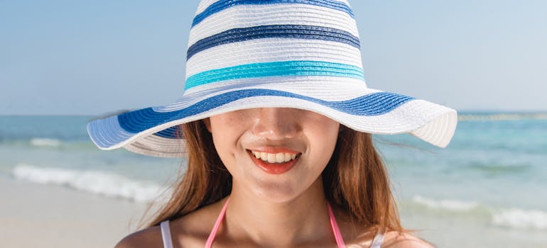 a woman wearing a hat on the beach and thinking about the signs it's time to move to a new city