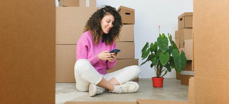 Woman with moving boxes and a plant, representing non-allowable items like perishables.