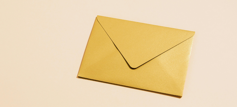 Golden envelope for snail mail to stay connected with loved ones after moving.