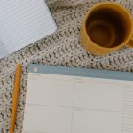 an orange cup and an orange pen next to a planner you might need to organize your Costa Mesa move in a week