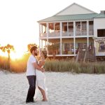 a couple hugging in front of a beach house and thinking of the important questions to ask when buying a home in Newport Beach