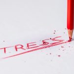 a red pencil writing the word "stress" on a piece of paper