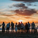 a group of people watching a sunset at the beach