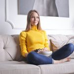 a woman sitting on a white couch after deciding to live alone in Long Beach CA