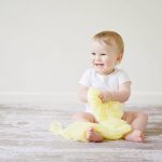 a toddler is smiling while holding a yellow blanket