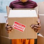 a woman holding a box which contains fragile items