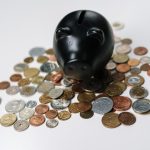 a black piggy bank on top of a pile of coins