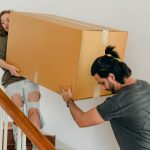 two people carrying a large box