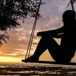 a woman sitting on a swing and thinking to herself: "How does moving help your mental health"