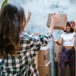 two girls tossing a cardboard box to each other